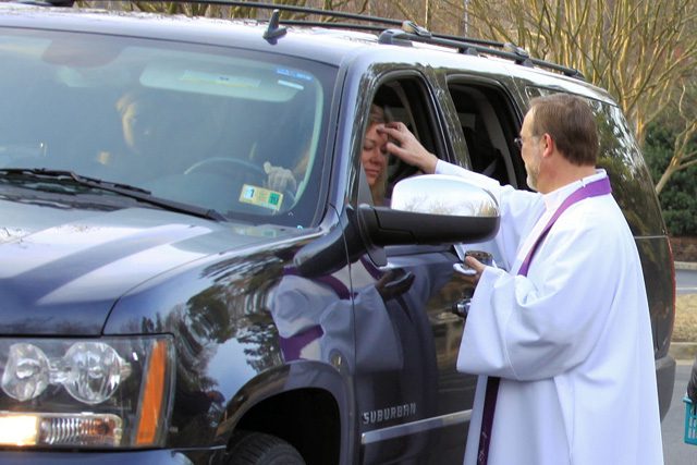 Pastor Larry giving ashes to a person in a car.