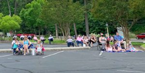 people sitting in lawn chairs in parking lot for worship