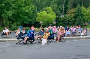 people sitting in lawn chairs in parking lot for worship