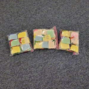 three bags of knitted prayer squares